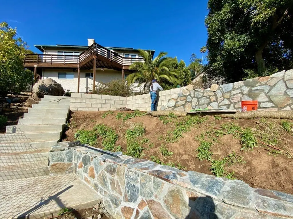 Stone being installed over a block retaining wall