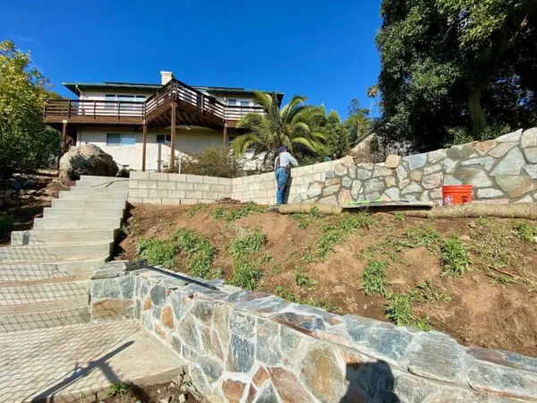 Stone being installed over a block retaining wall