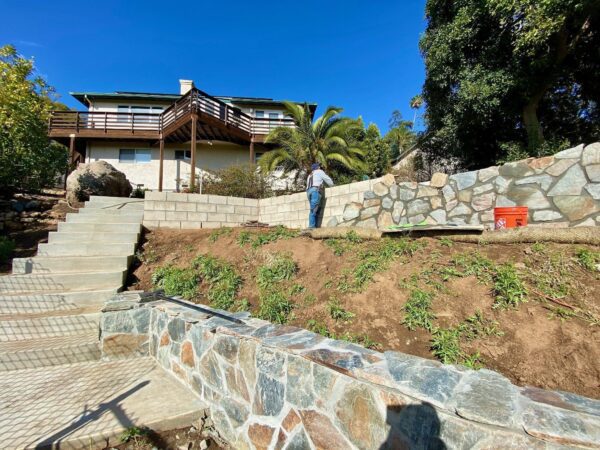 Stone being installed over a block retaining wall